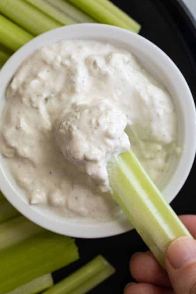 Blue cheese sauce being scooped with a celery stick