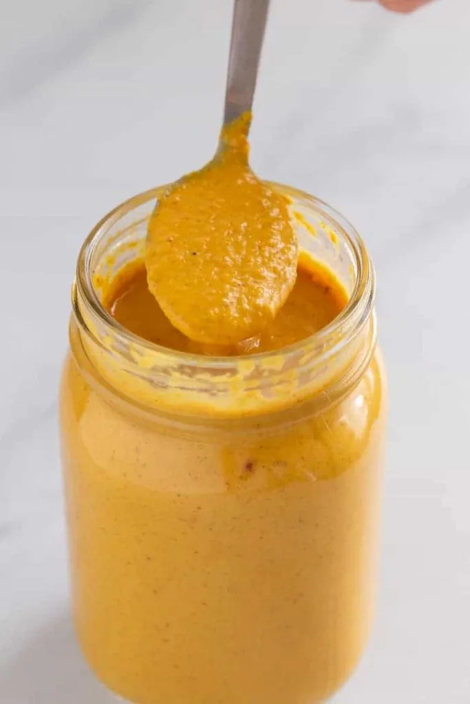 Butter chicken sauce in a jar with a spoon scooping out some