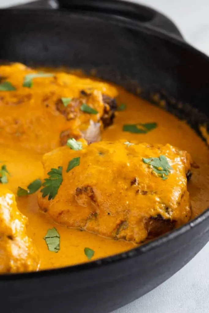 side view of butter chicken sauce in a pan with chicken