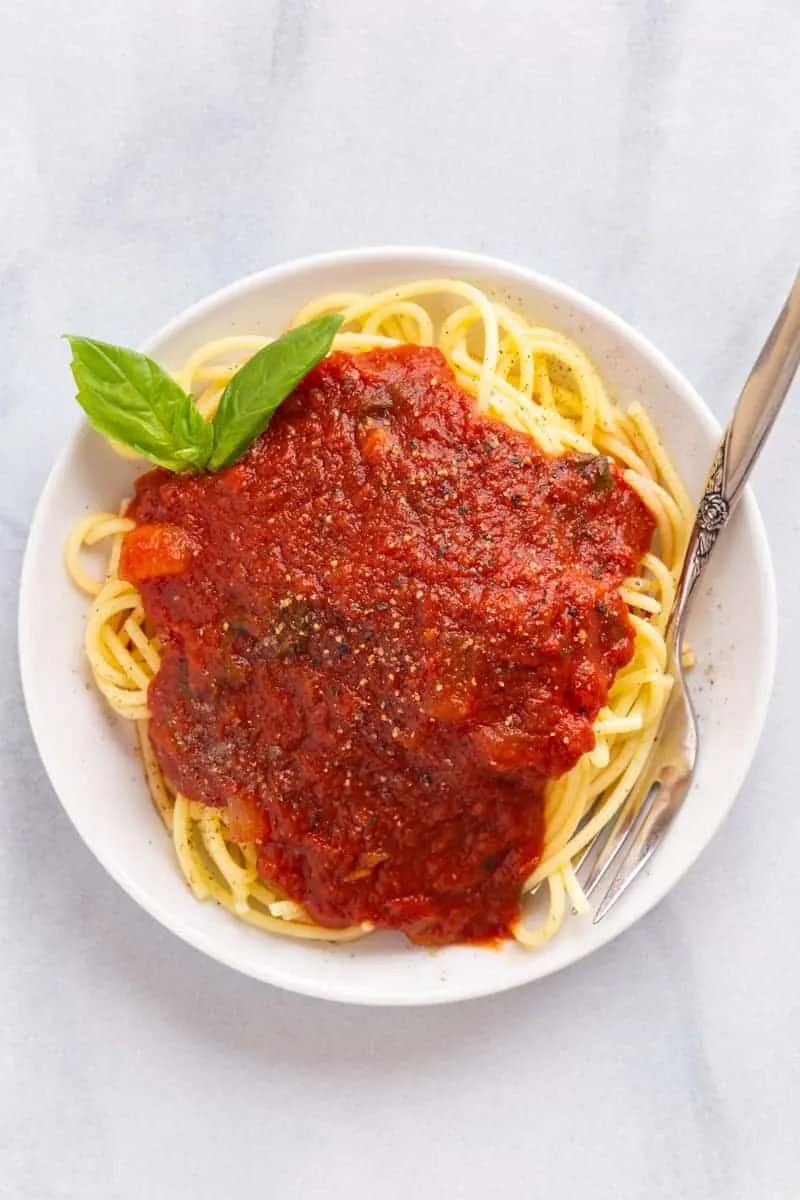 Spaghetti on a white plate with fork.