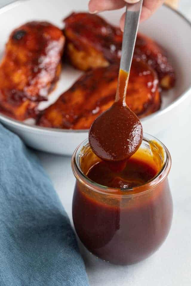 A jar of Jack Daniels sauce with a spoon scooping some out