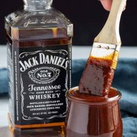 Jack Daniels sauce in a jar next to a bottle of Jack Daniels whiskey