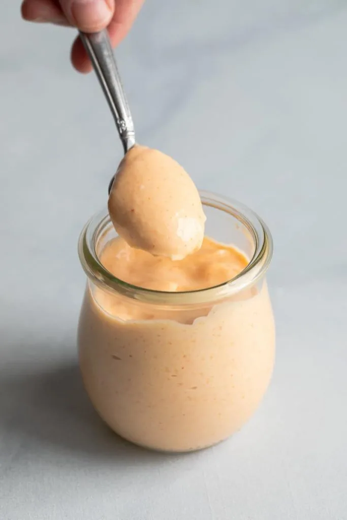 Yum Yum Sauce in a glass jar with a spoon