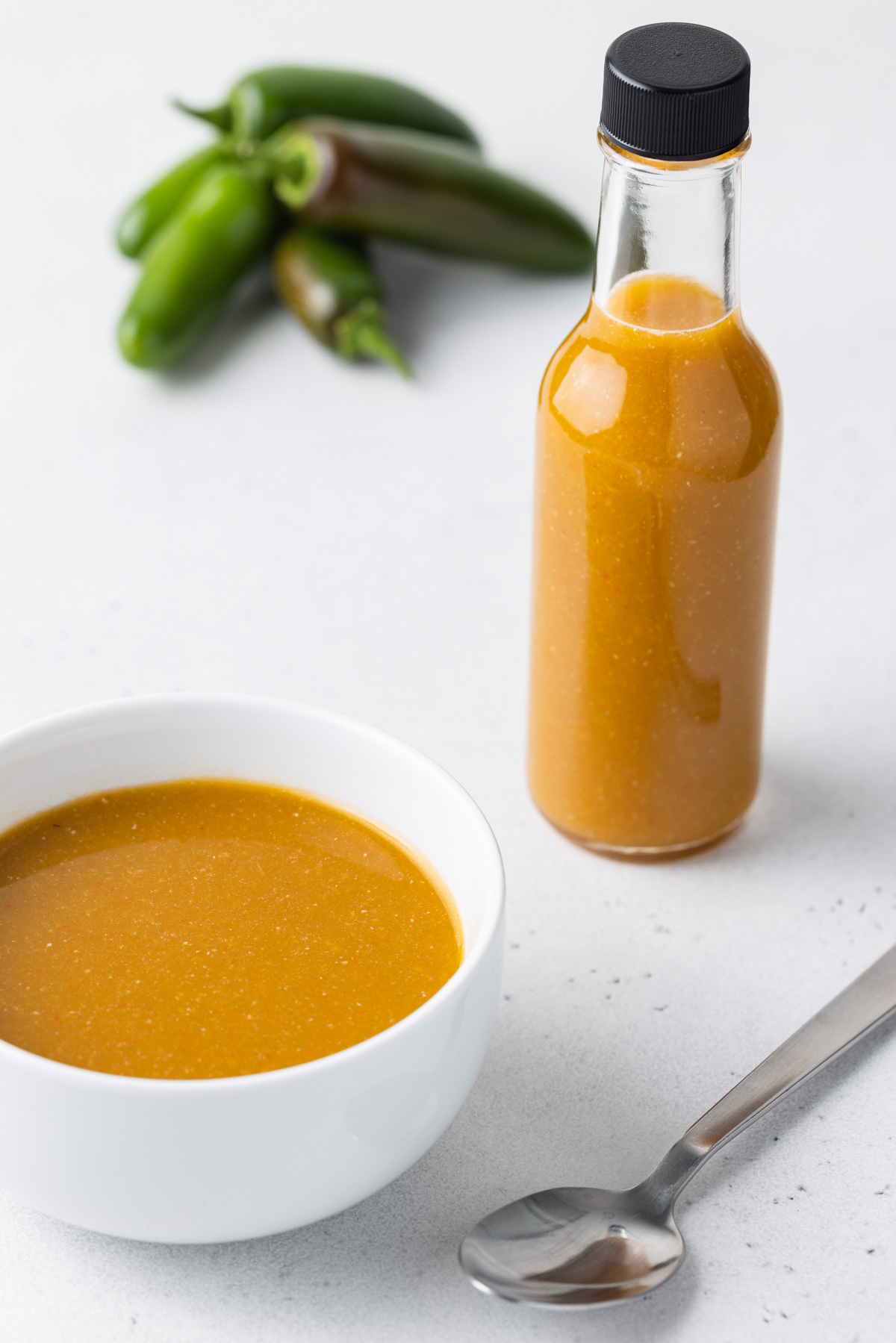 Jalapeno hot sauce in a bowl and bottle.