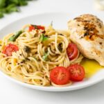 Angled view of pasta and chicken white plate.