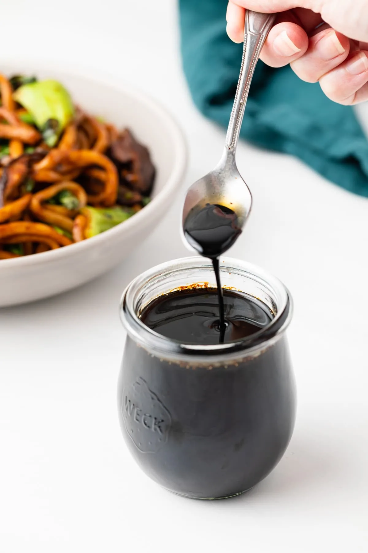 Udon sauce in glass jar with a spoon.