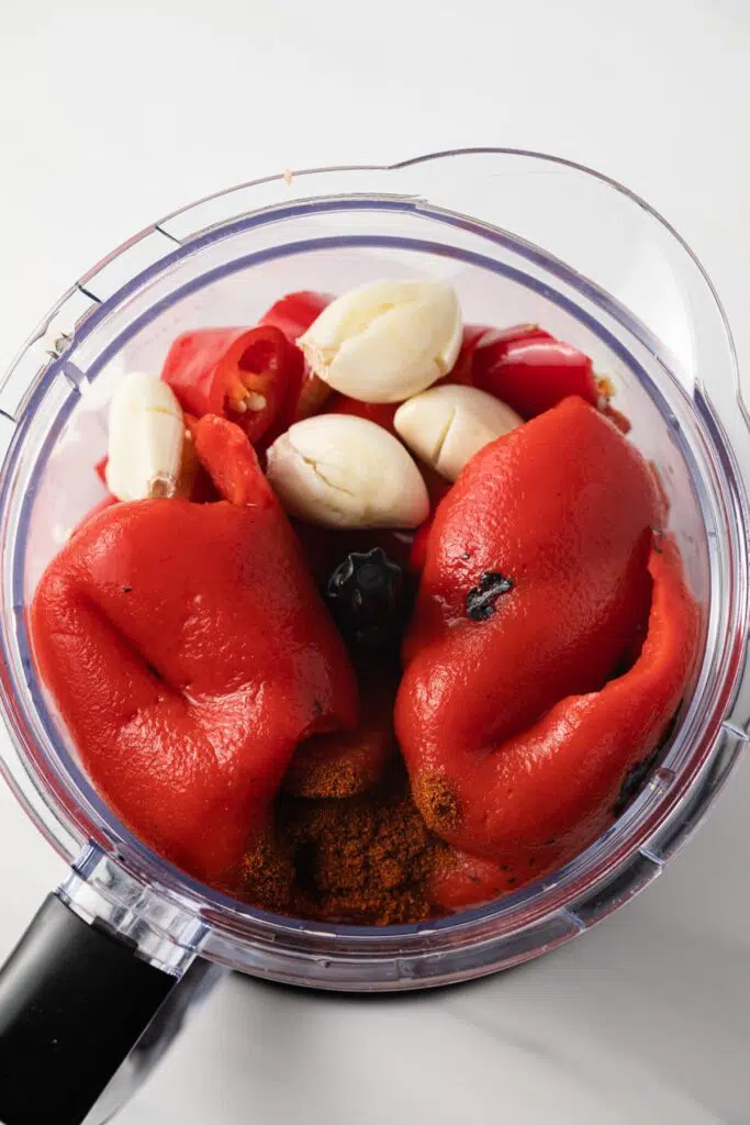 Peppers and garlic in the bowl of a food processor.
