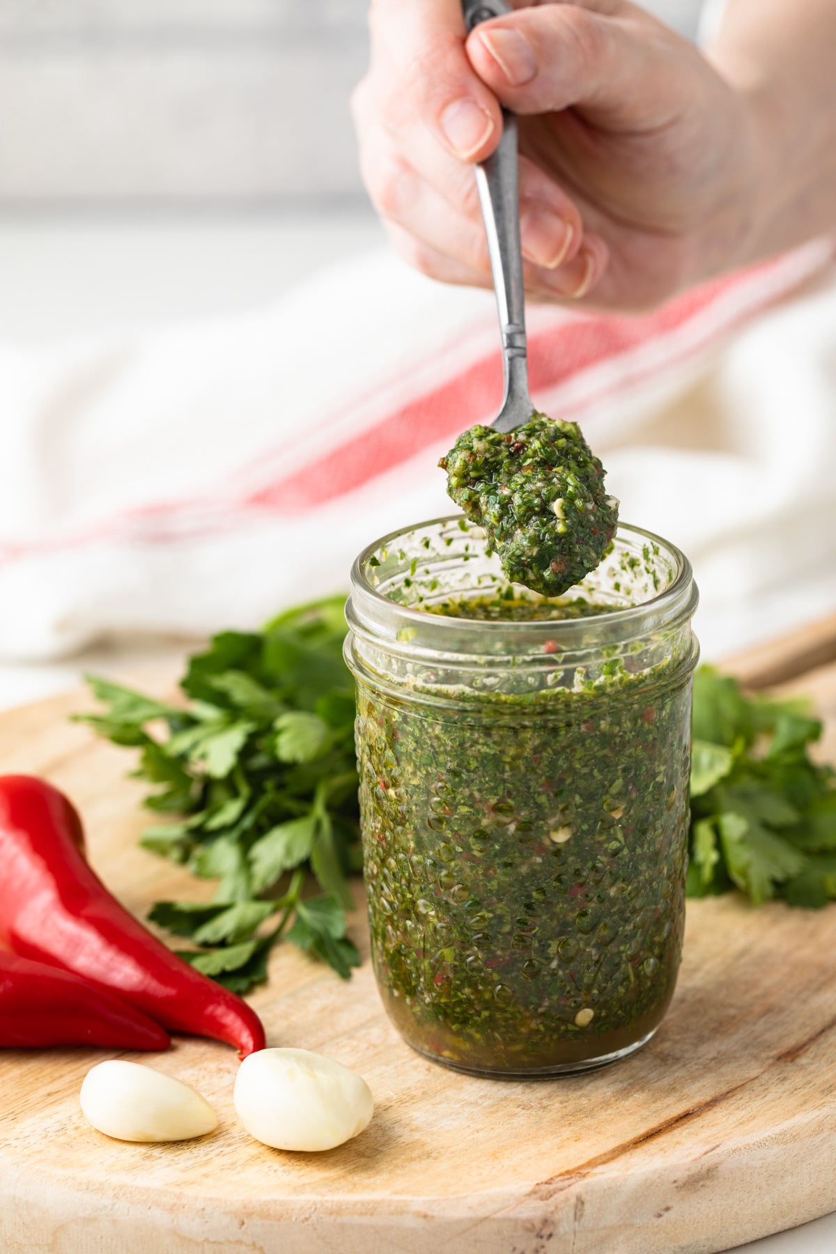Cilantro chimichurri in a glass jar with a spoon.