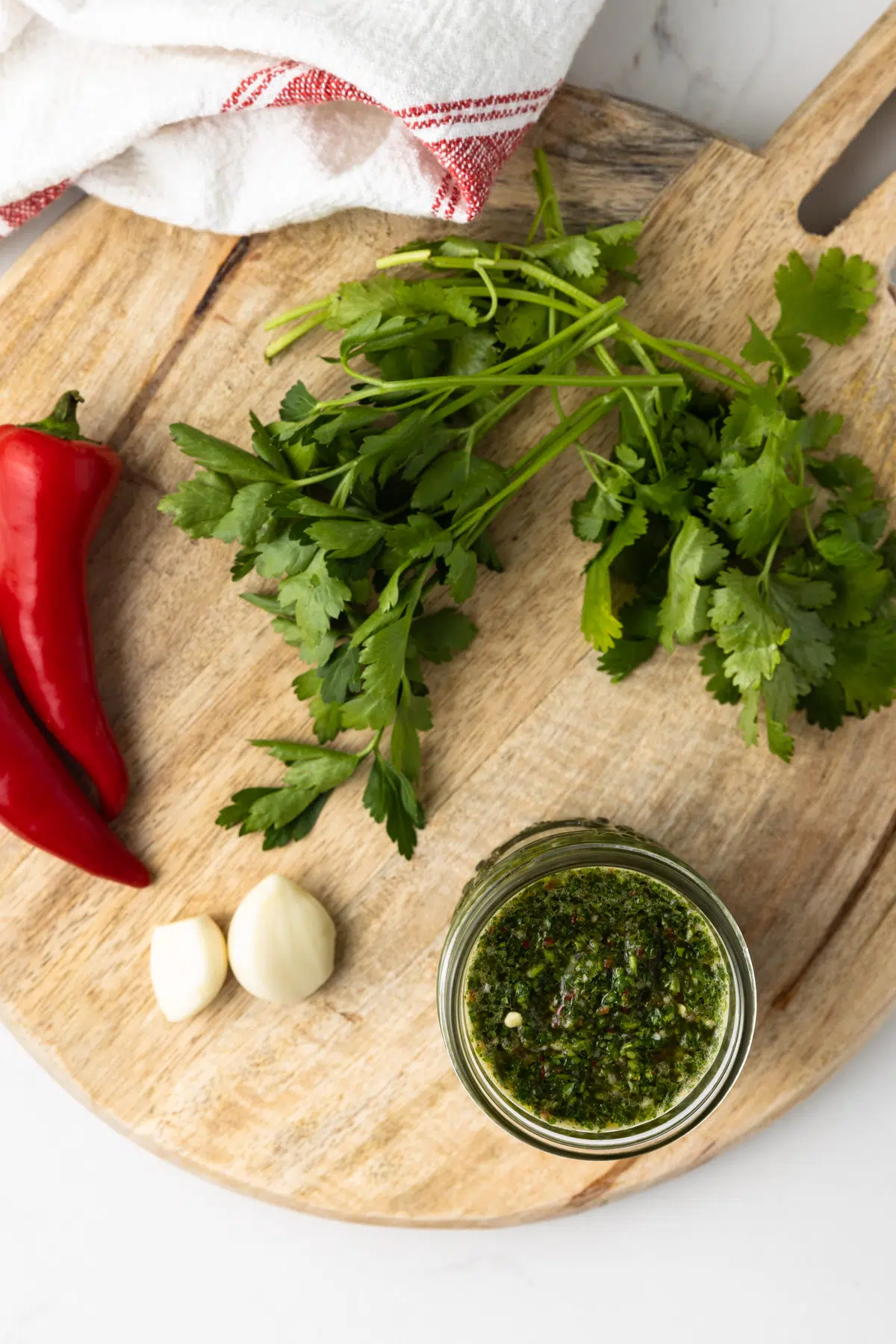 Overheat of chimichurri with ingredients on rough wooden board.