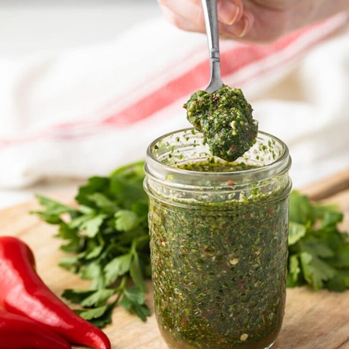 Cilantro chimichurri in a glass jar with a spoon.