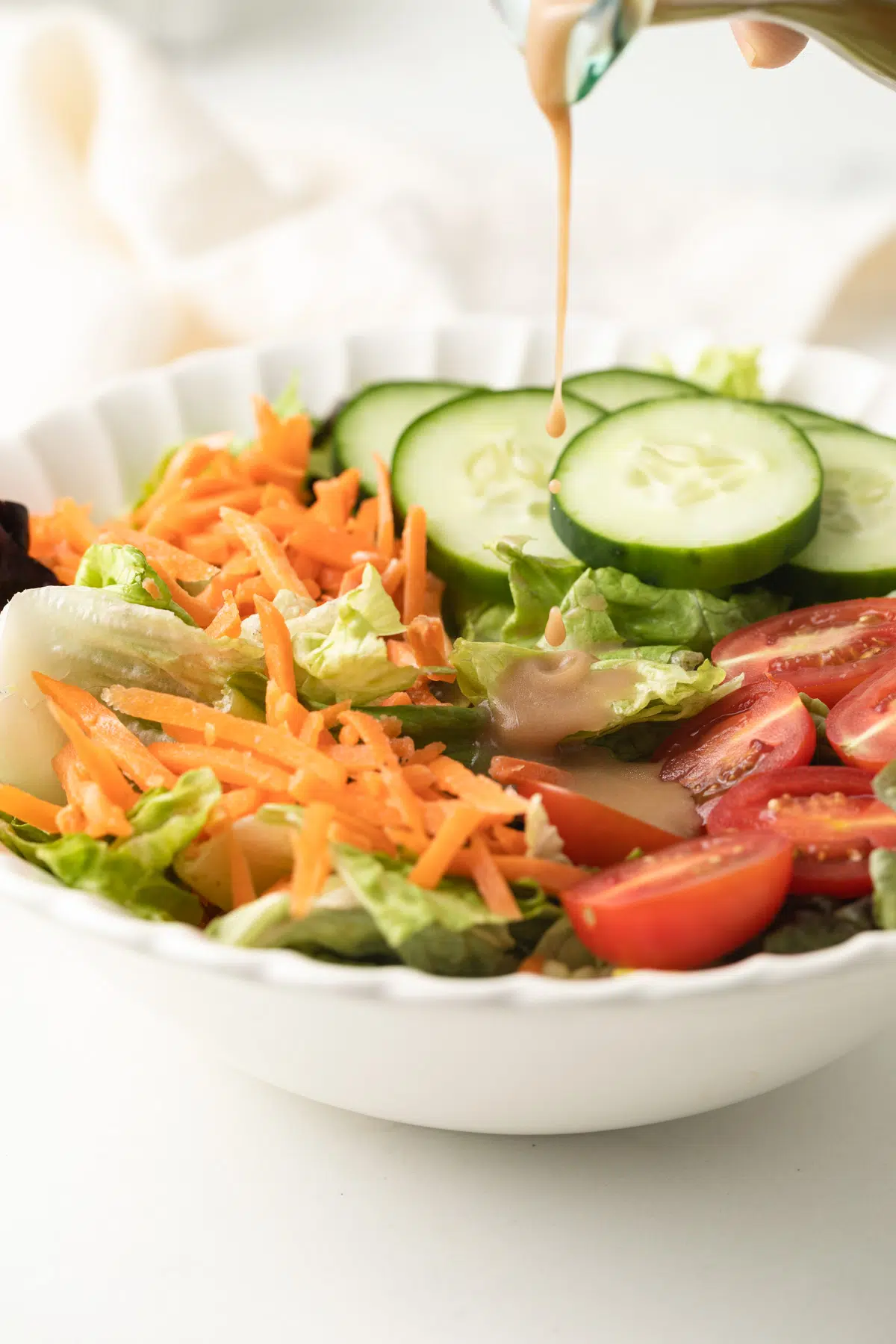 Creamy balsamic dressing being poured over salad.