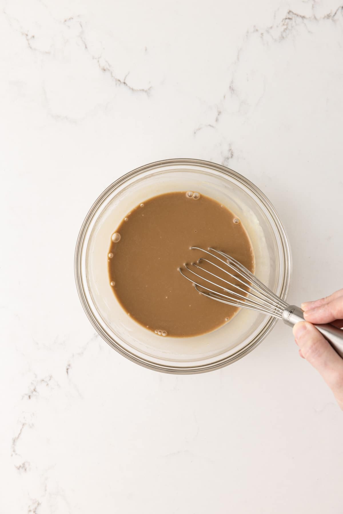 Balsamic dressing in a glass bowl with whisk.