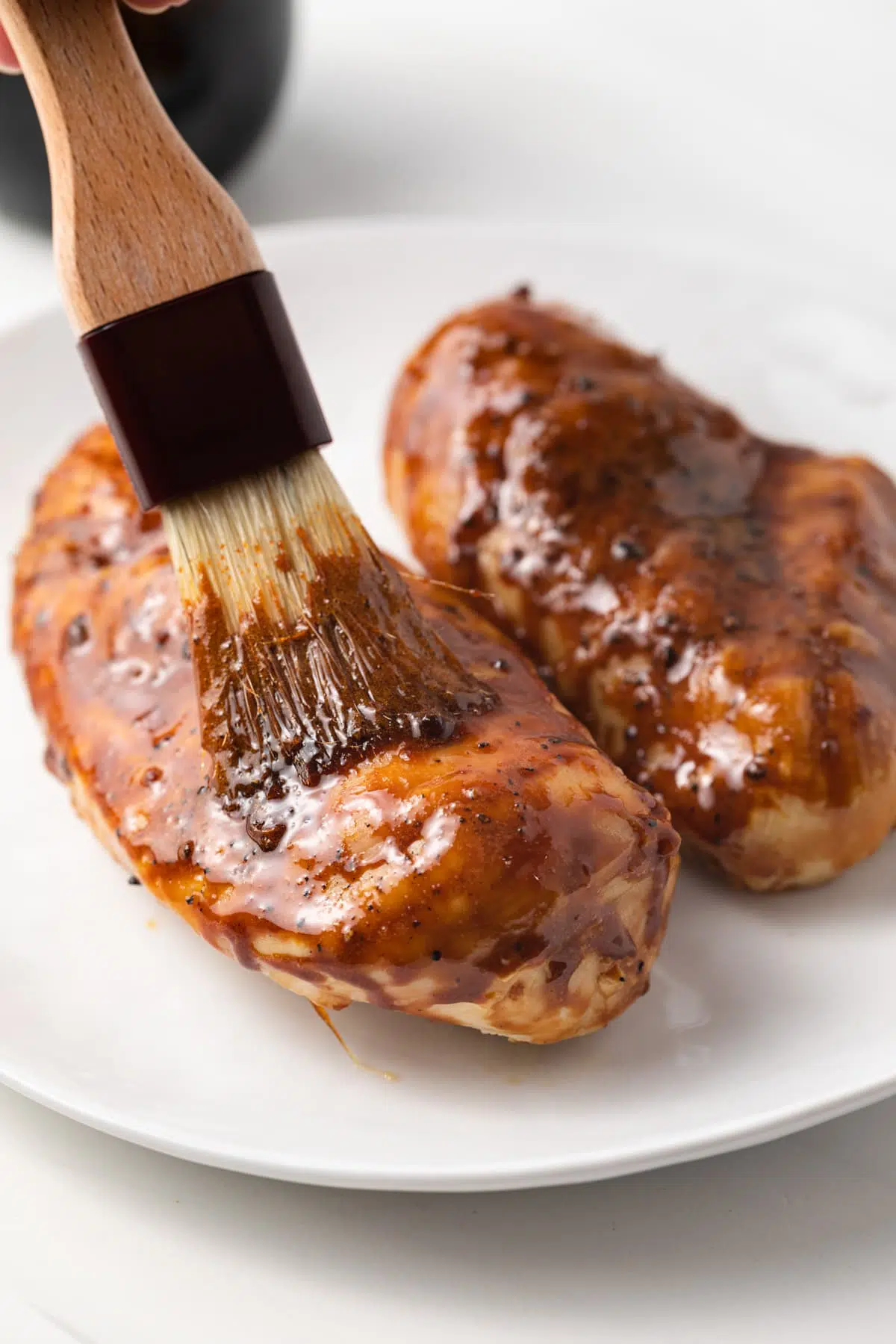 Brushing Hawaiian teriyaki sauce over chicken breast.