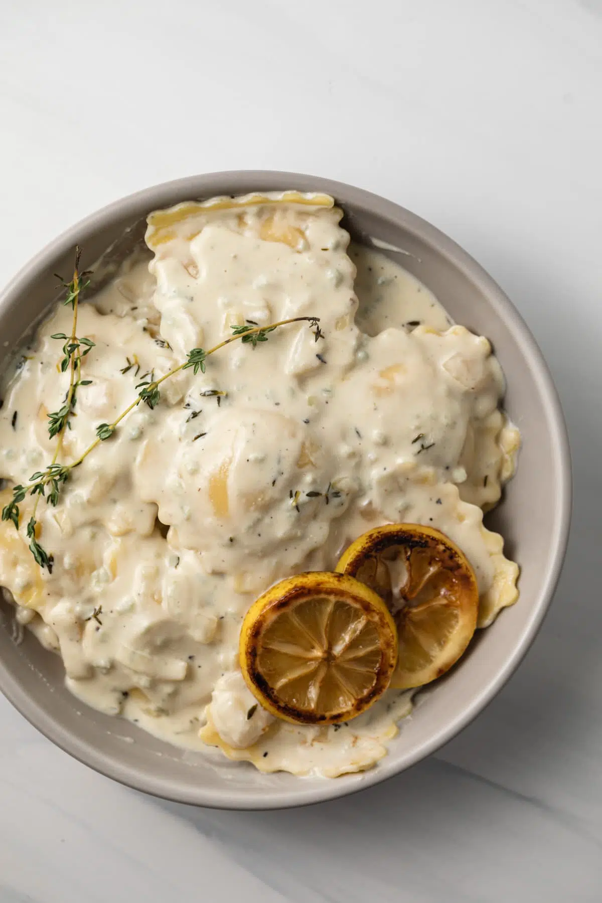 Lobster ravioli coated in sauces in a bowl.