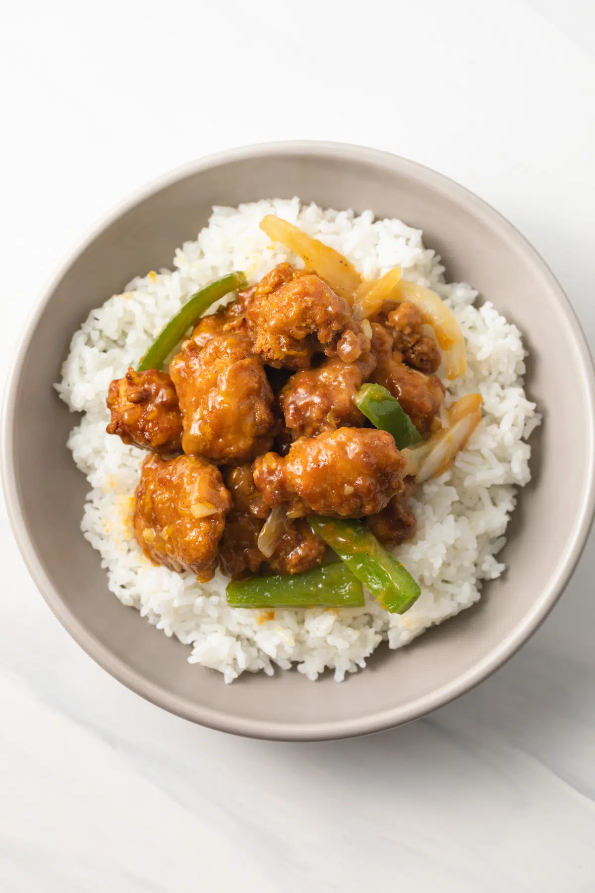 Chicken coated in orange ginger sauce over rice.
