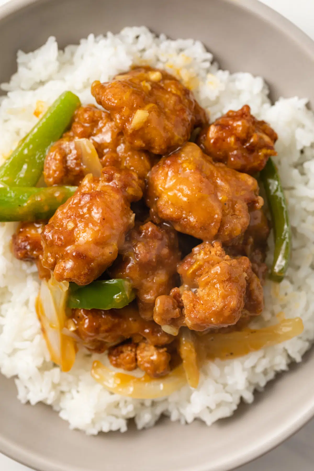 Close up of chicken coated in orange ginger sauce over rice.