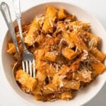 Bolognese meat sauce over rigatoni in bowl.