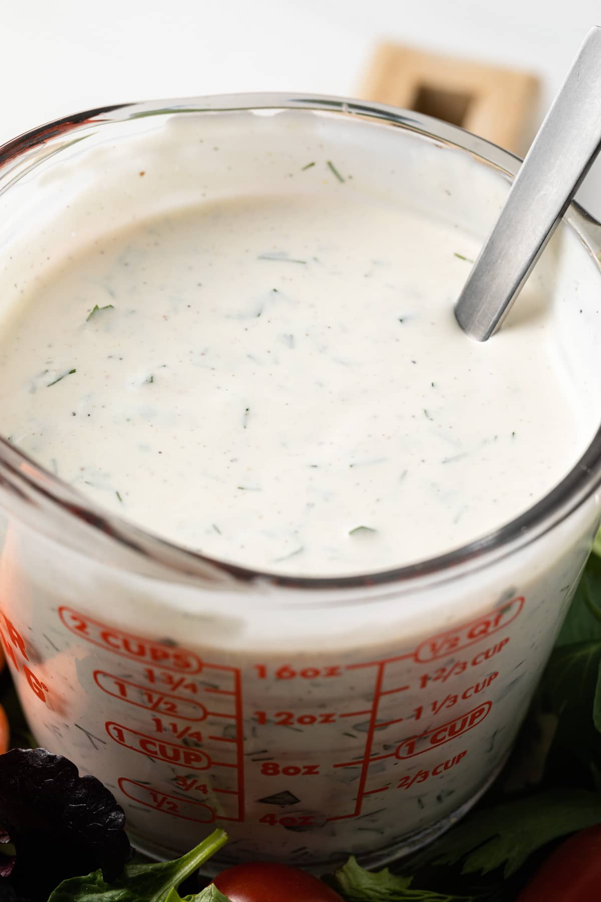 Close up of ranch dressing in glass measuring cup.