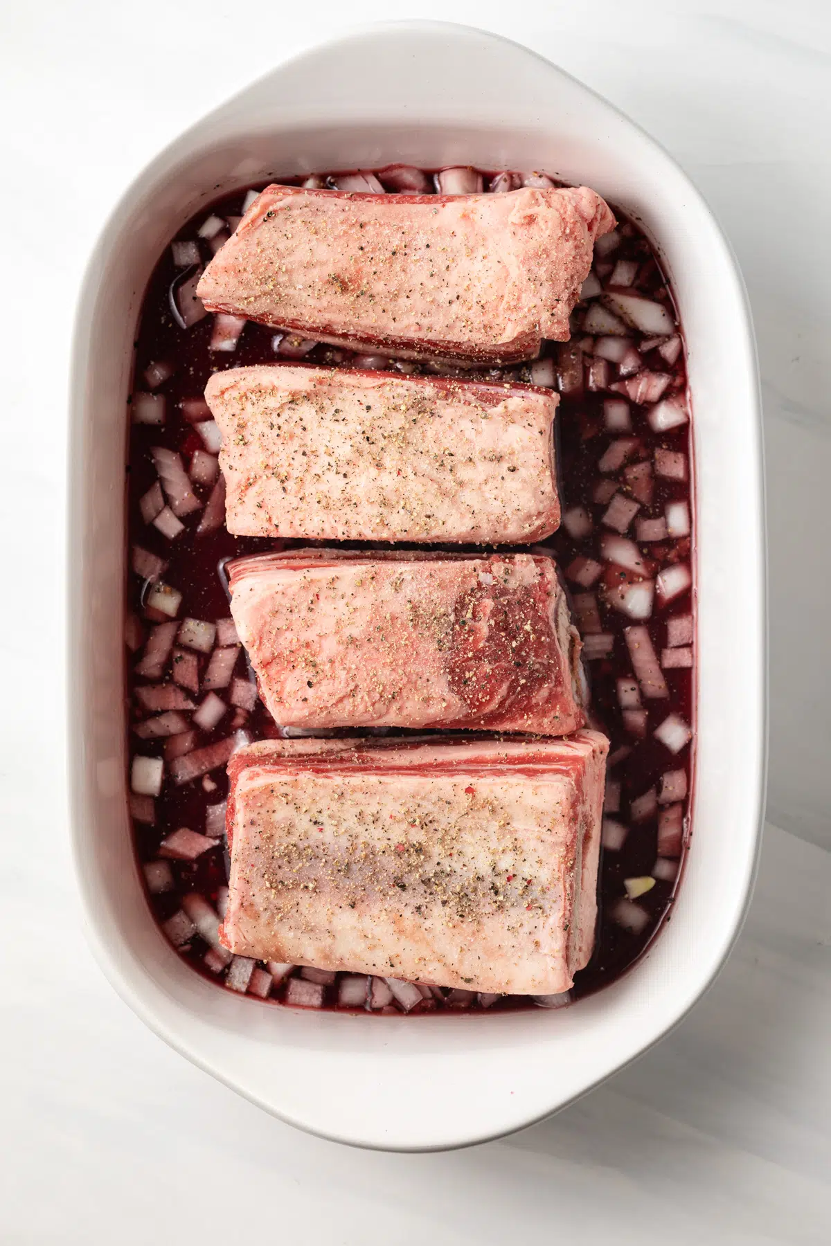 Uncooked beef short ribs in pan.