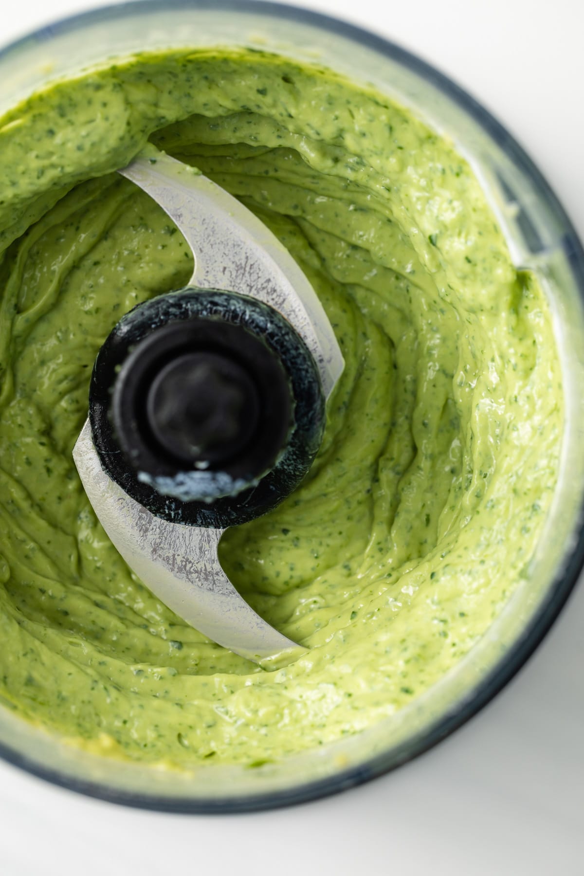 Avocado cilantro dressing blended in the bowl of a food processer.
