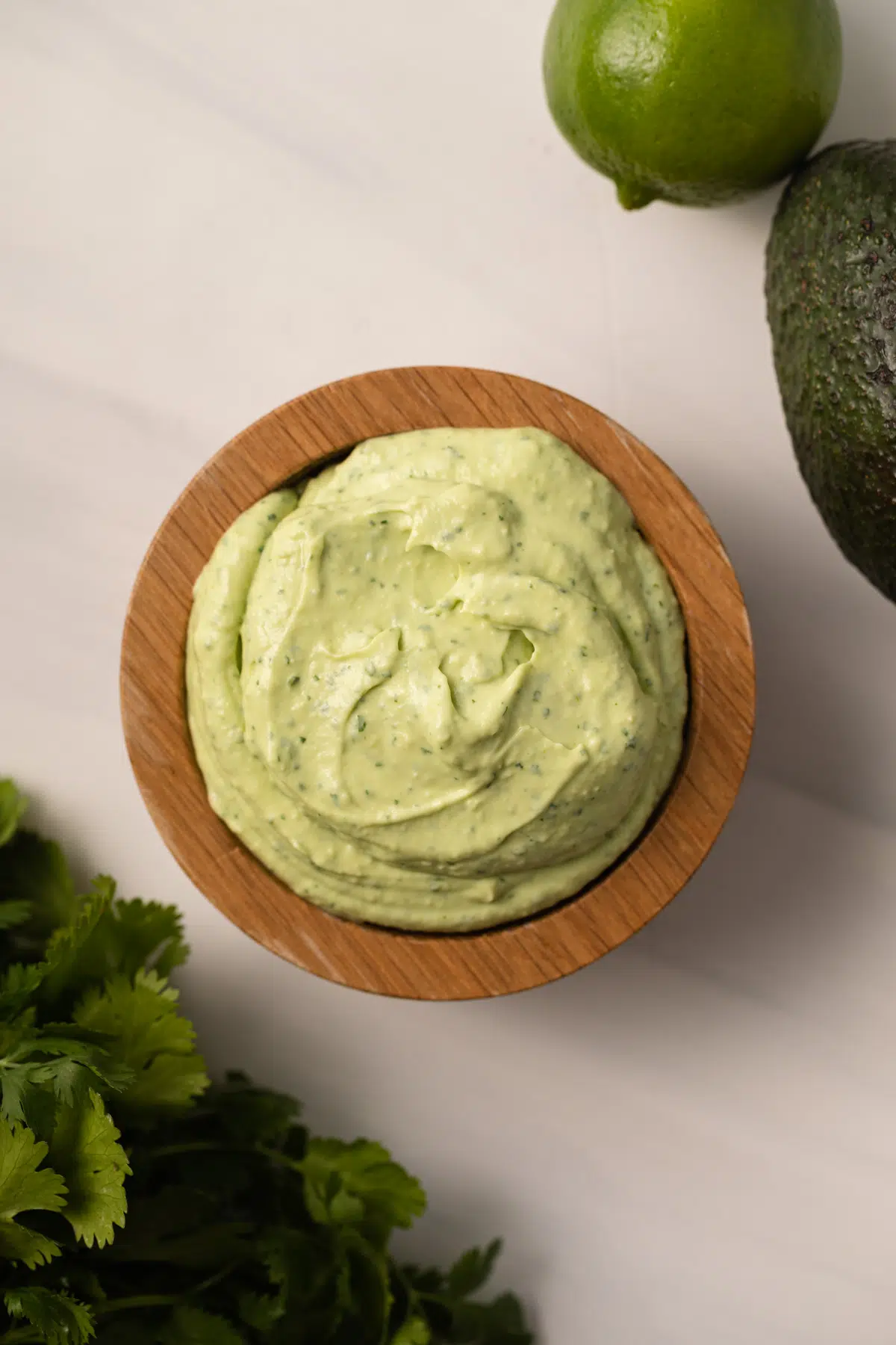 Overhead of avocado crema in a wooden bowl.