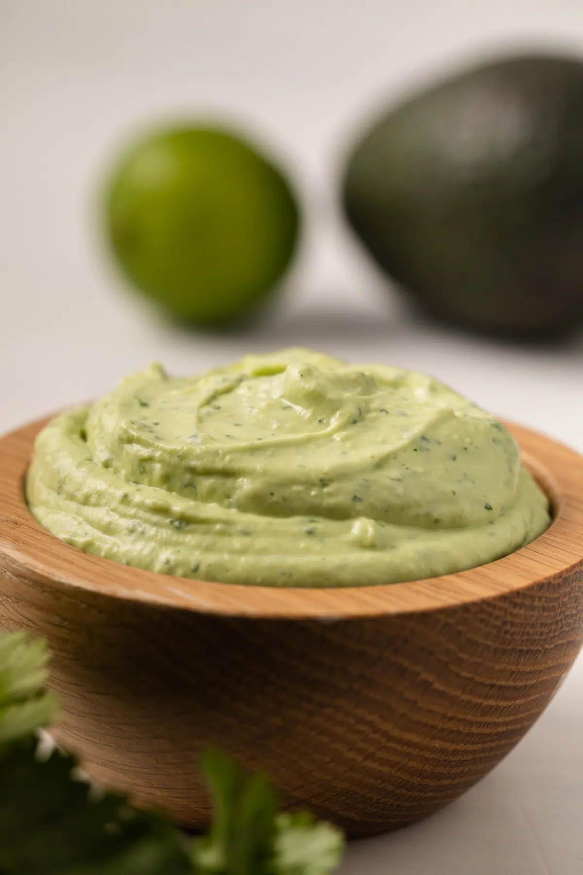 Side view of avocado crema in a wooden bowl.