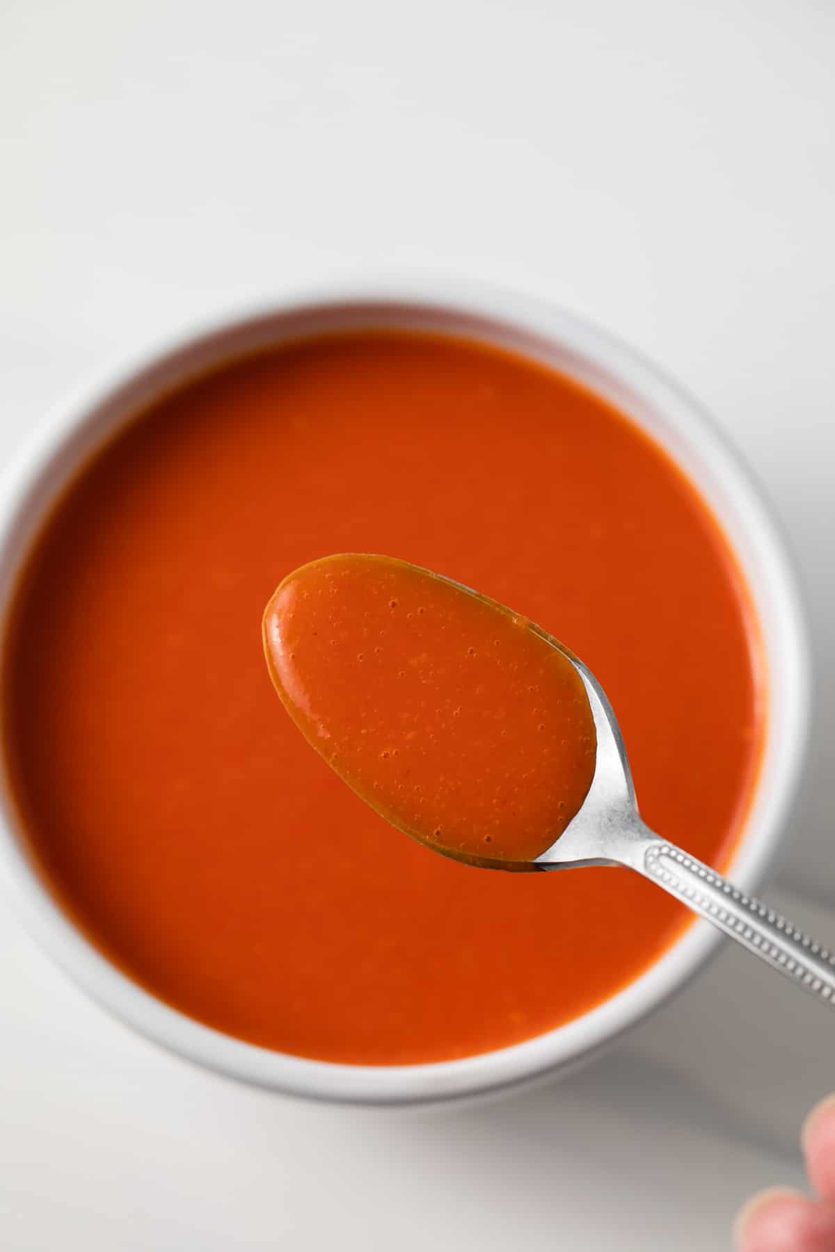 Cayenne pepper hot sauce in a white bowl with a spoon.
