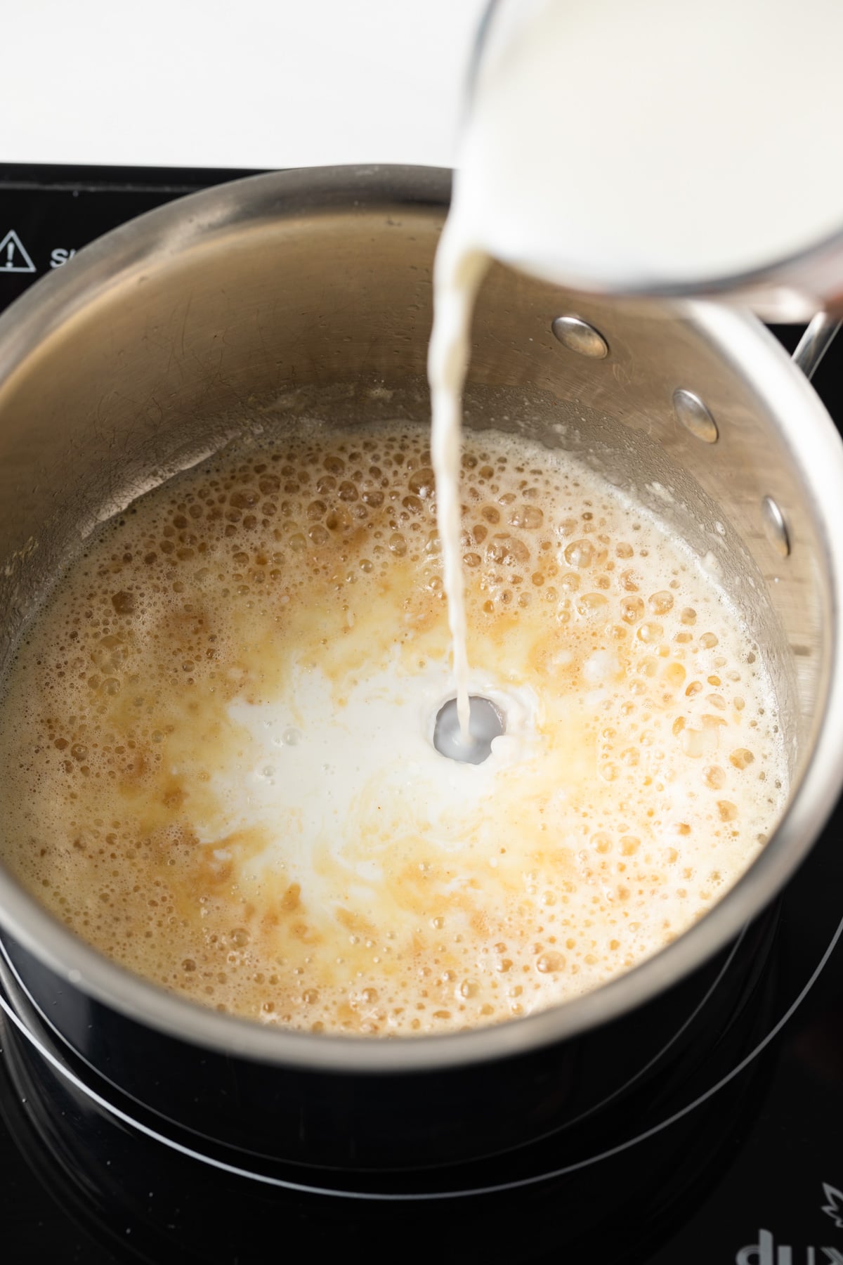 Milk added to roux in pan.
