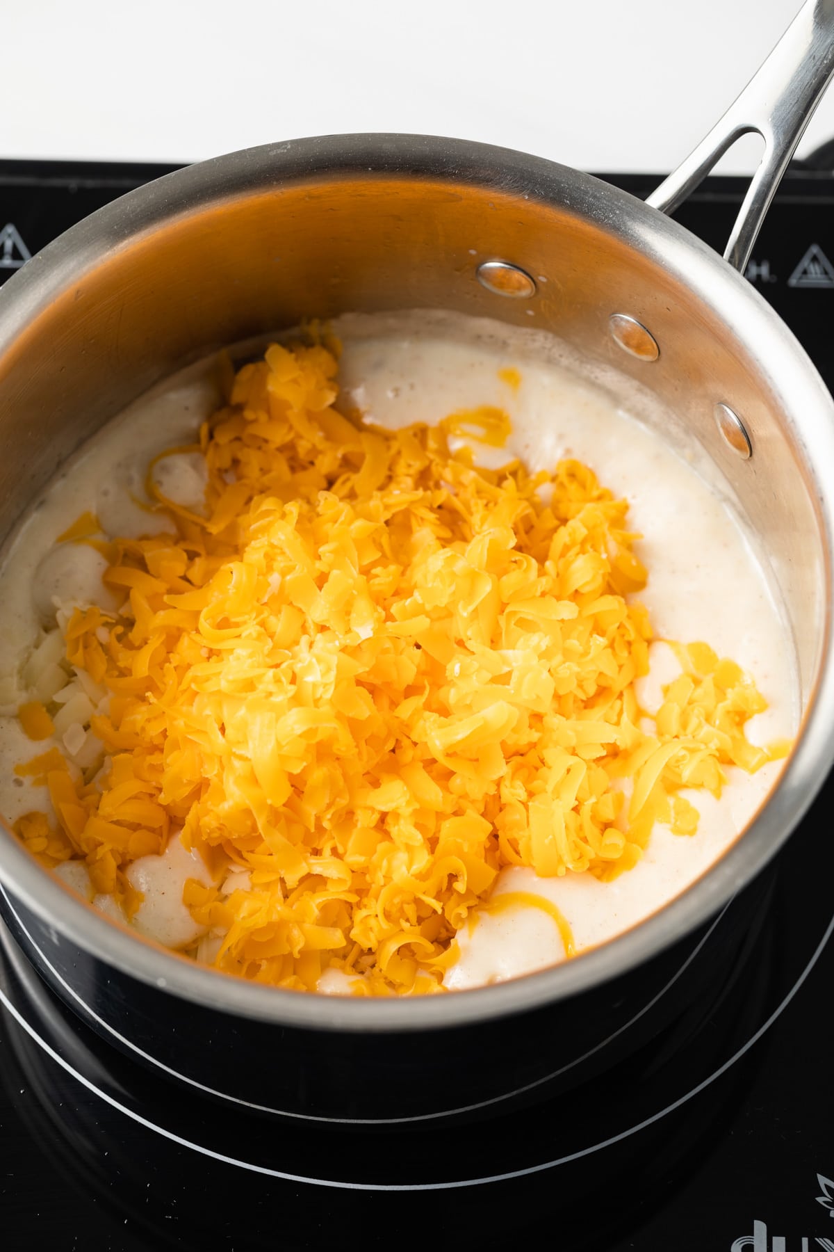 Cheese added to sauce base in pan.