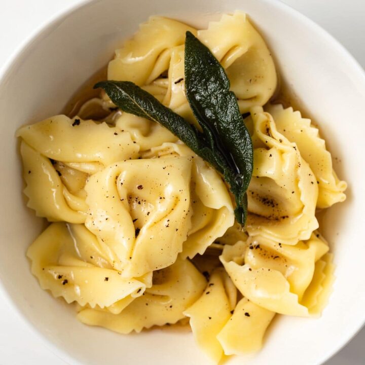 Tortellini with sage butter sauce in a white bowl.
