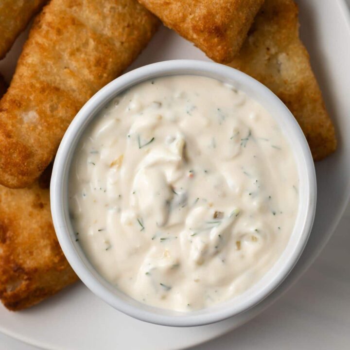Tartar sauce in white bowl with fish fillets.