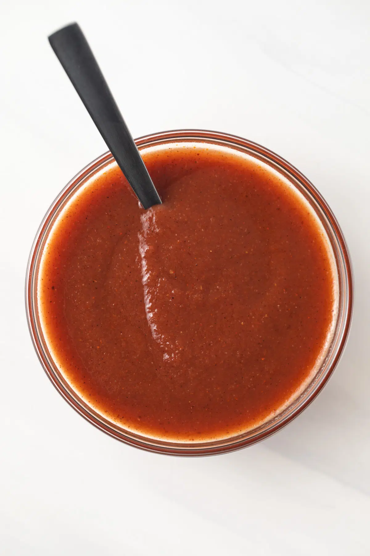 Homemade chili sauce in glass bowl with spoon.