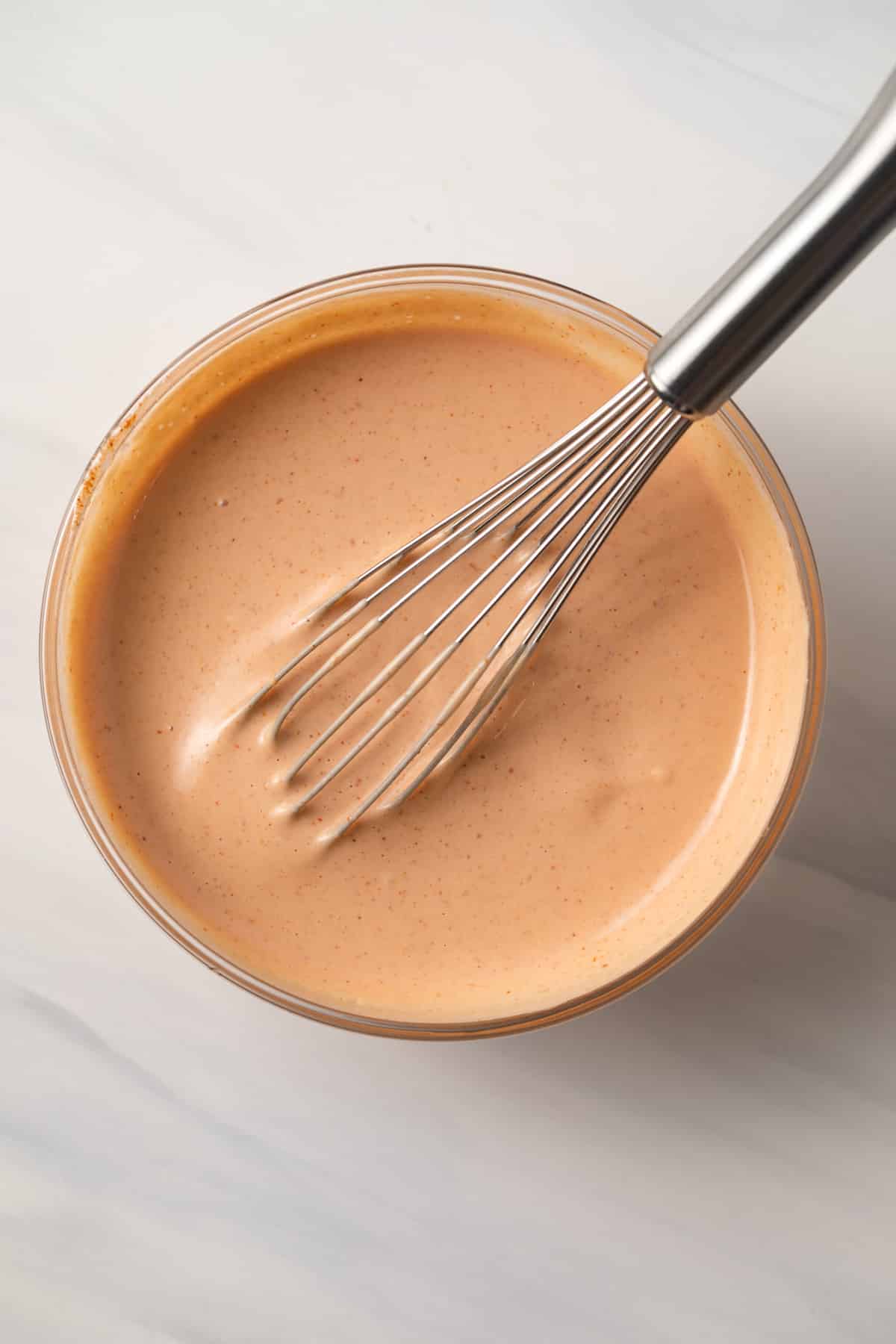 Comeback sauce in a glass bowl with whisk.