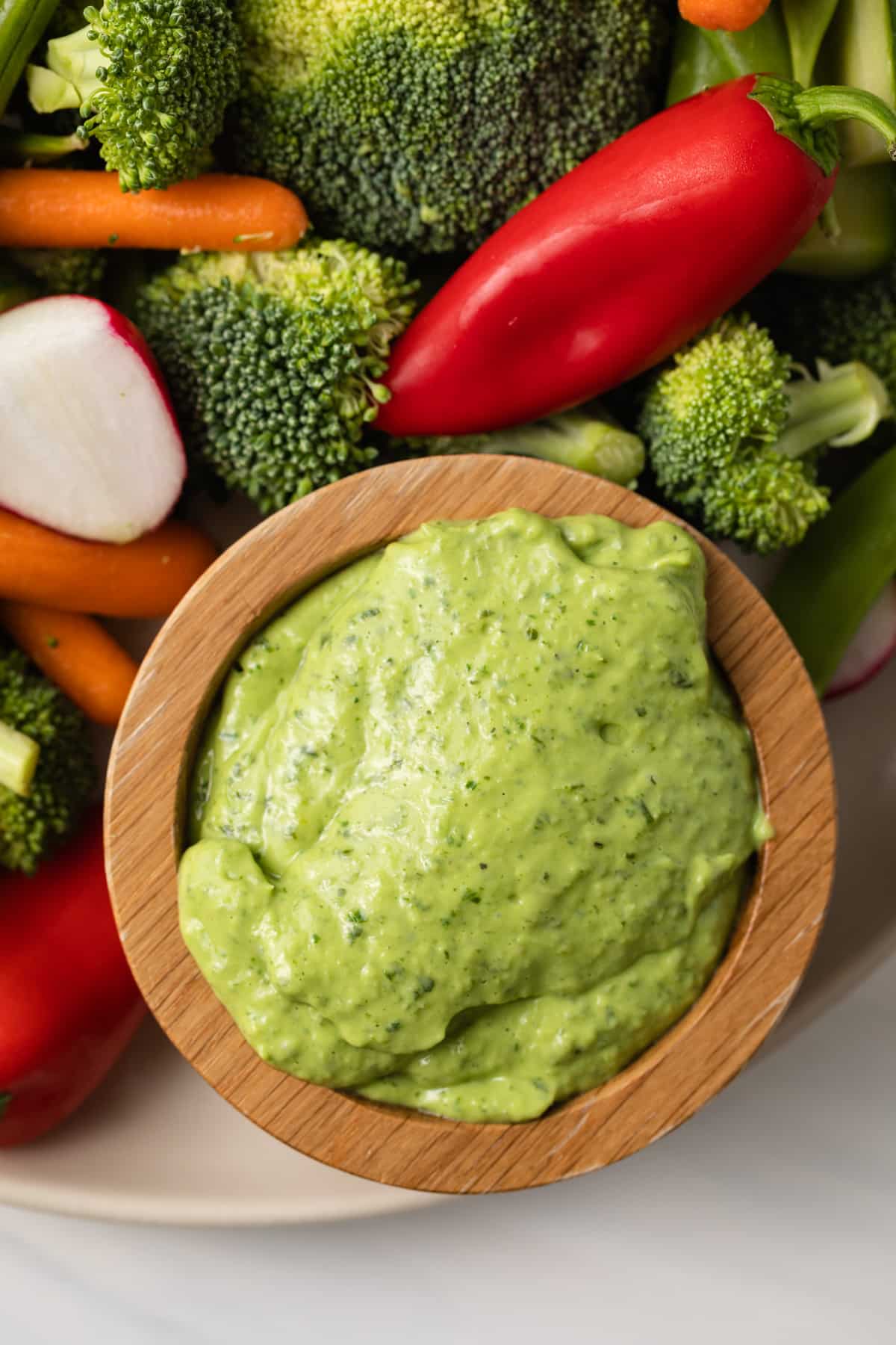 Close up of green goddess pesto sauce in a wooden bowl.