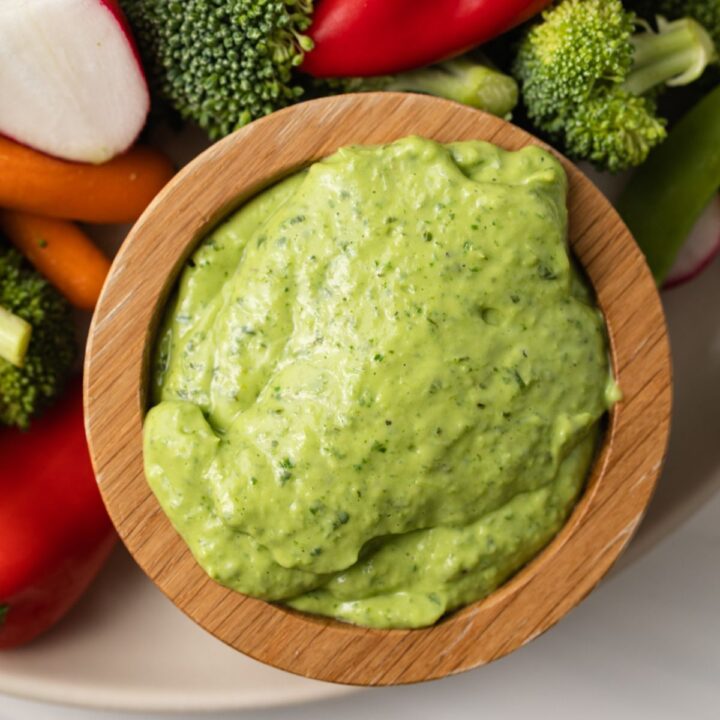 Close up of green goddess pesto sauce in a wooden bowl.