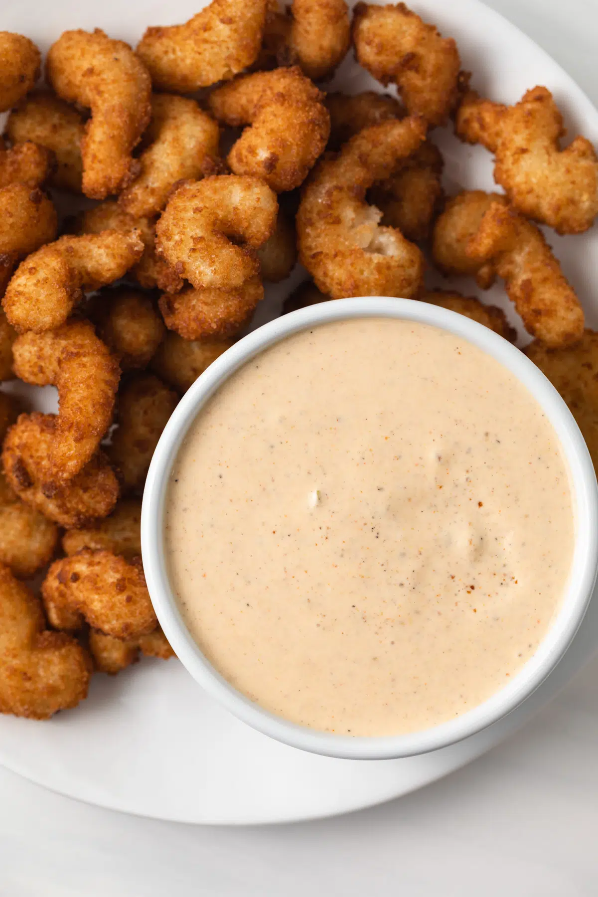 Remoulade sauce in white bowl with side of popcorn shrimp.