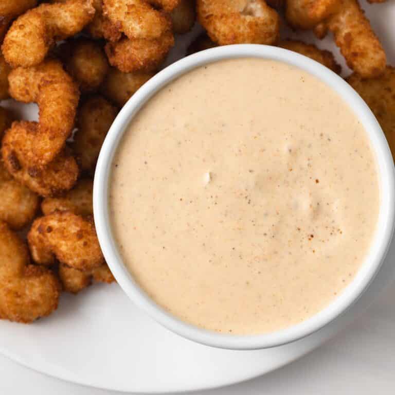 Remoulade sauce in white bowl with side of popcorn shrimp.
