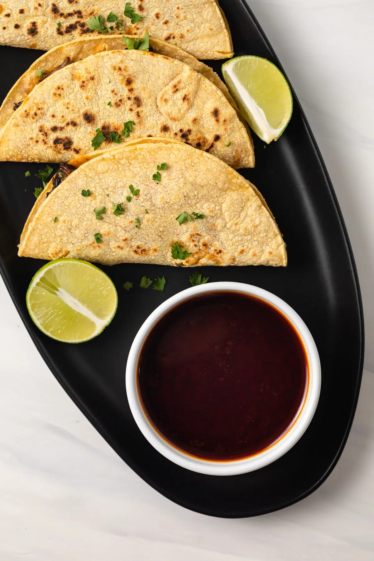 Consome in a white bowl with tacos to the side.