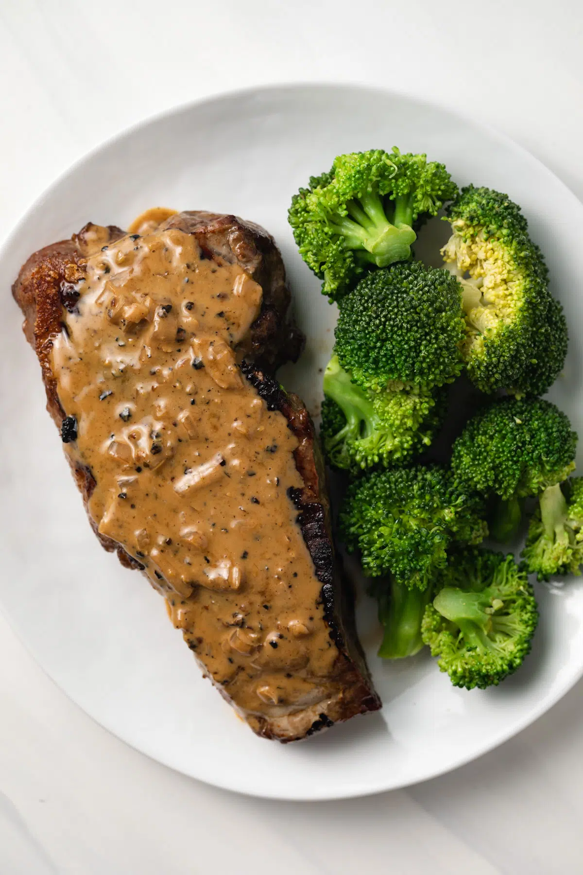 Overhead view of creamy peppercorn sauce over a steak.