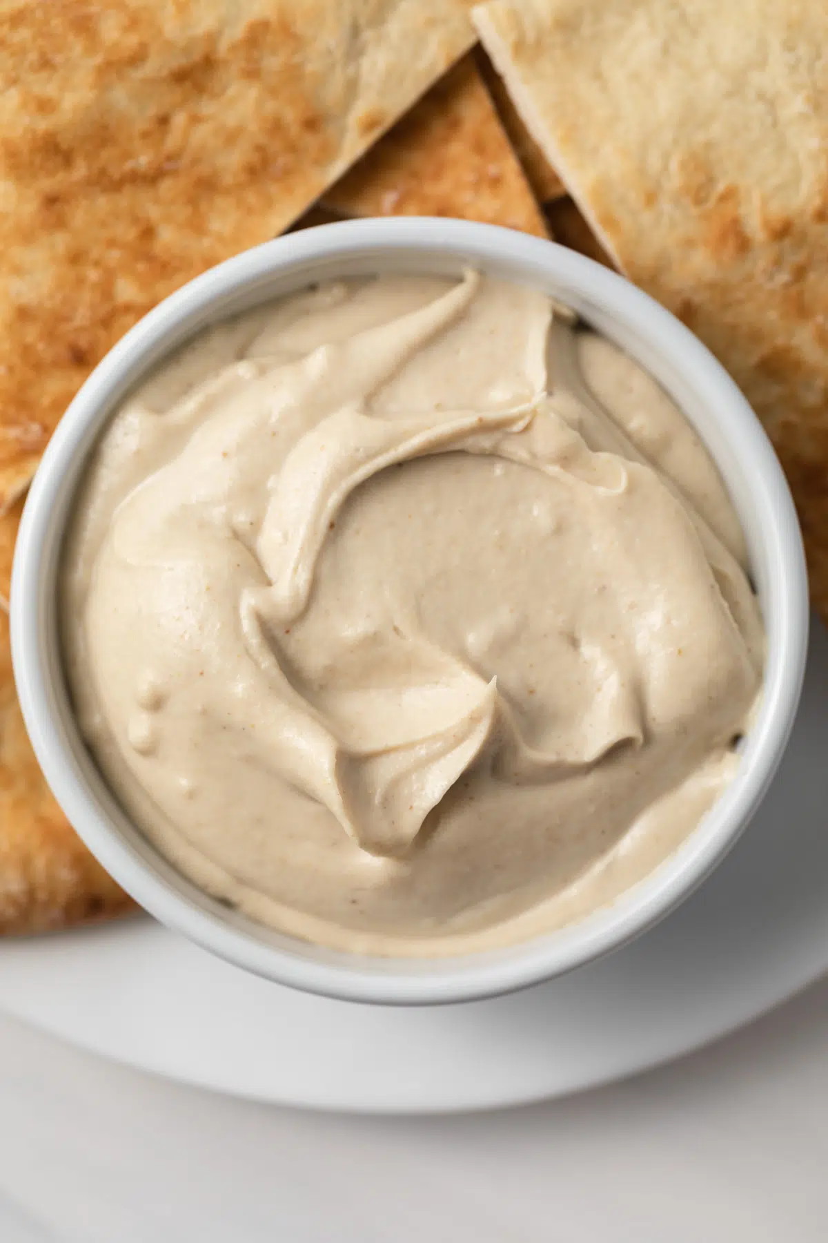 Close up of creamy tahini sauce in white bowl.