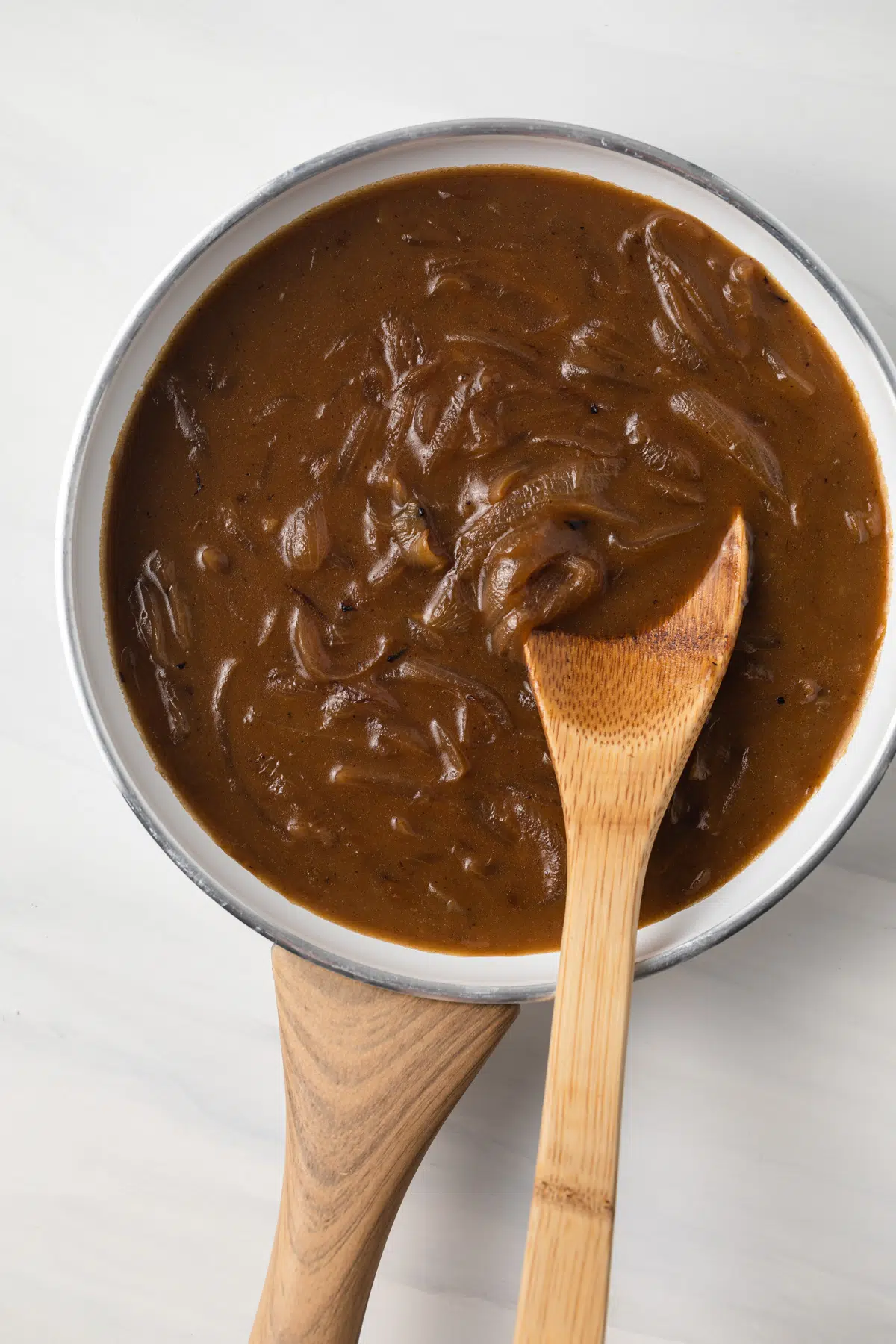 Onion gravy in a white fry pan.