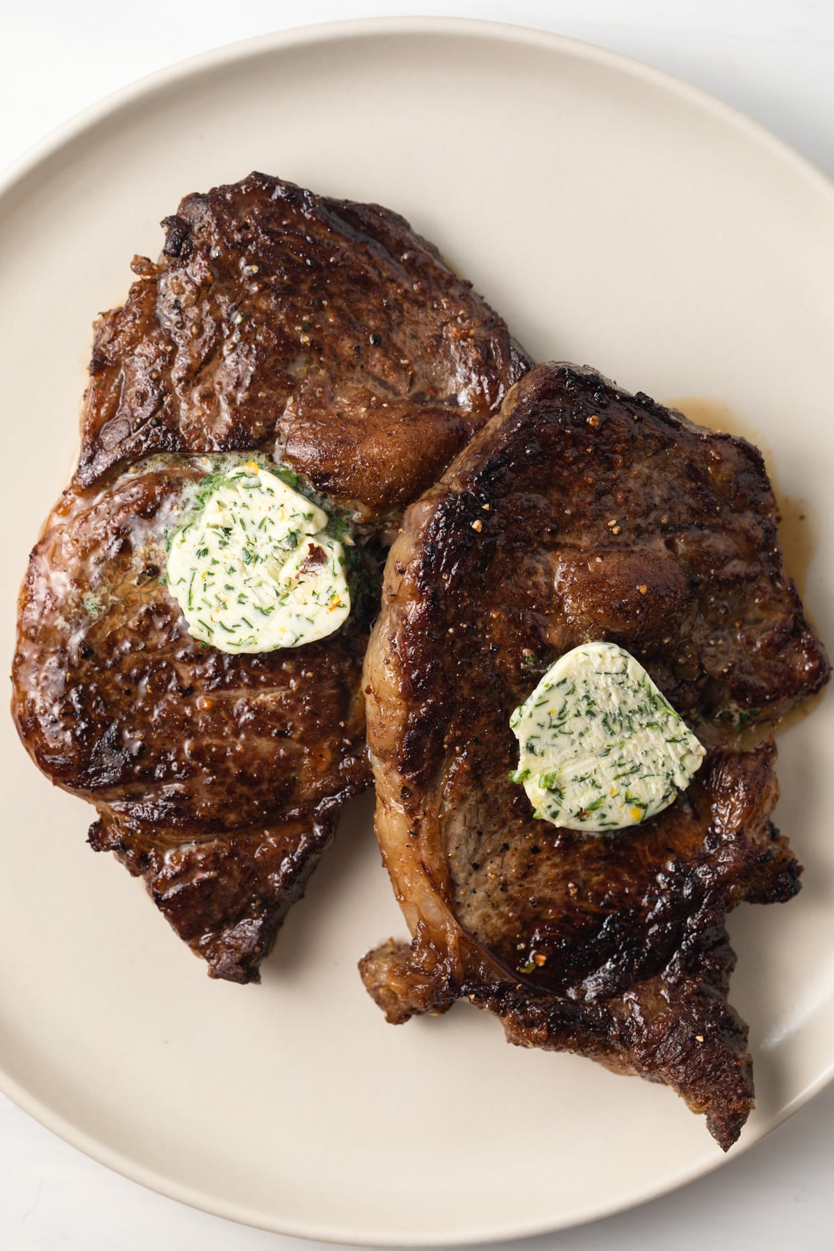 Two steaks with a pad of melty cowboy butter on top.