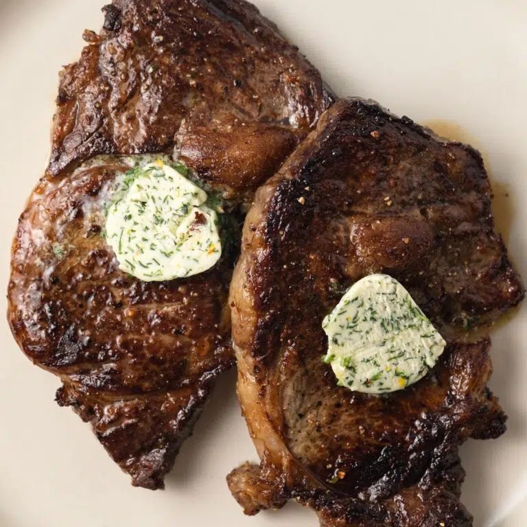 Two steaks with a pad of melty cowboy butter on top.