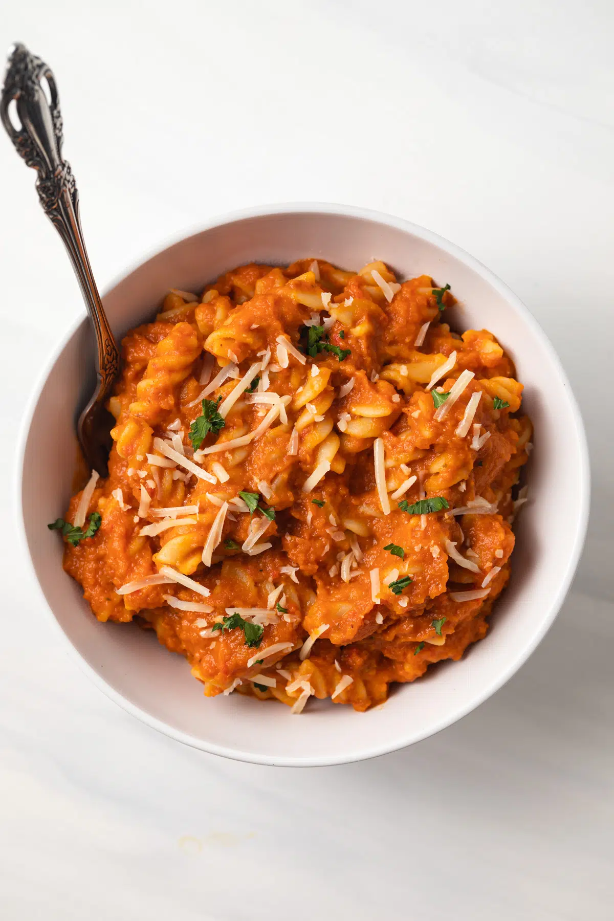 Creamy pumpkin sauce tossed with noodles in a bowl.