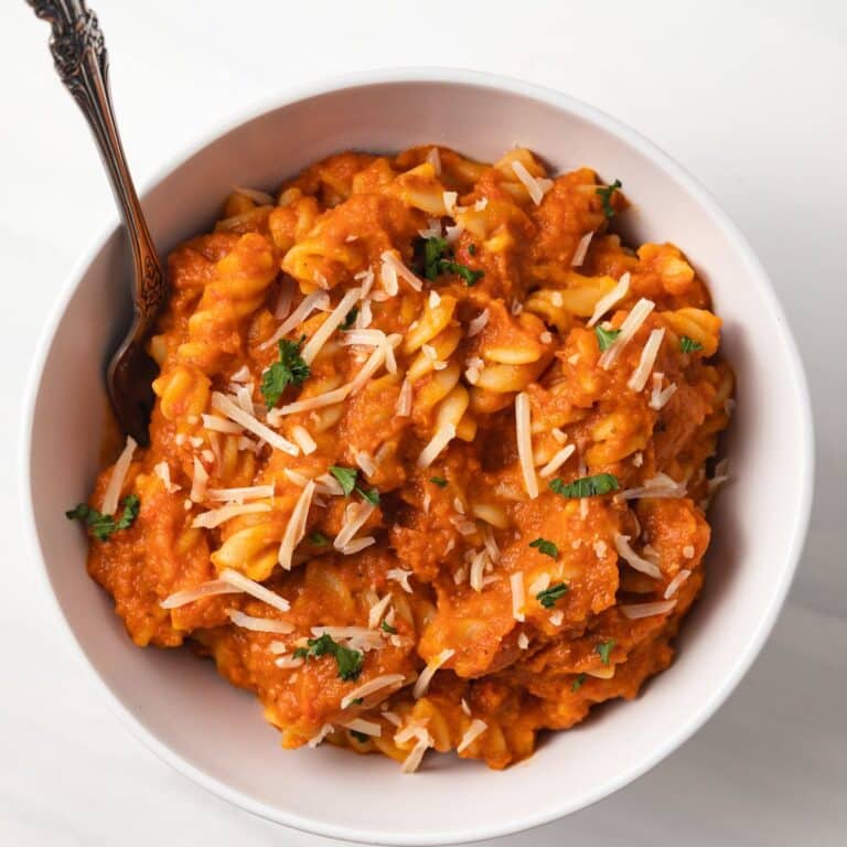 Creamy pumpkin sauce tossed with noodles in a bowl.
