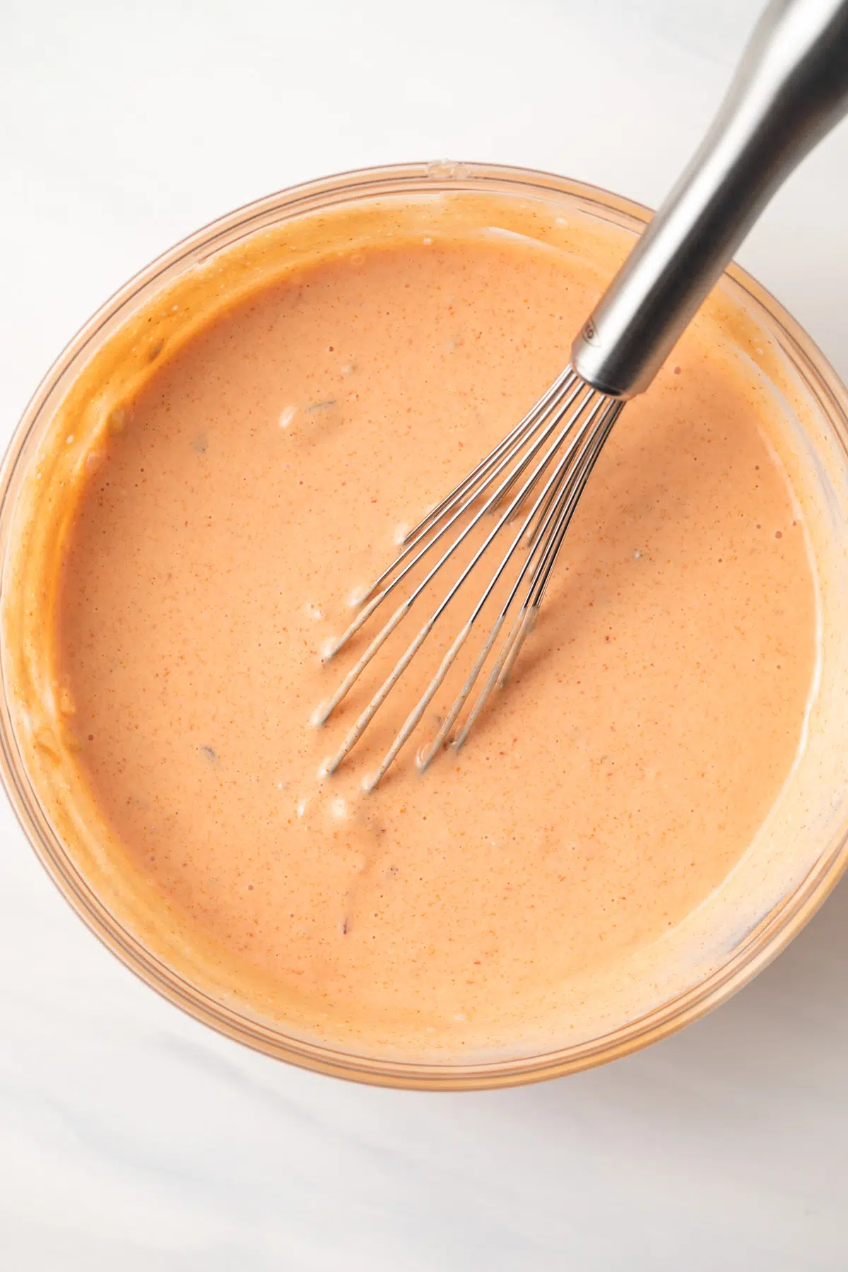 Creamy russian dressing whisked in a glass bowl.