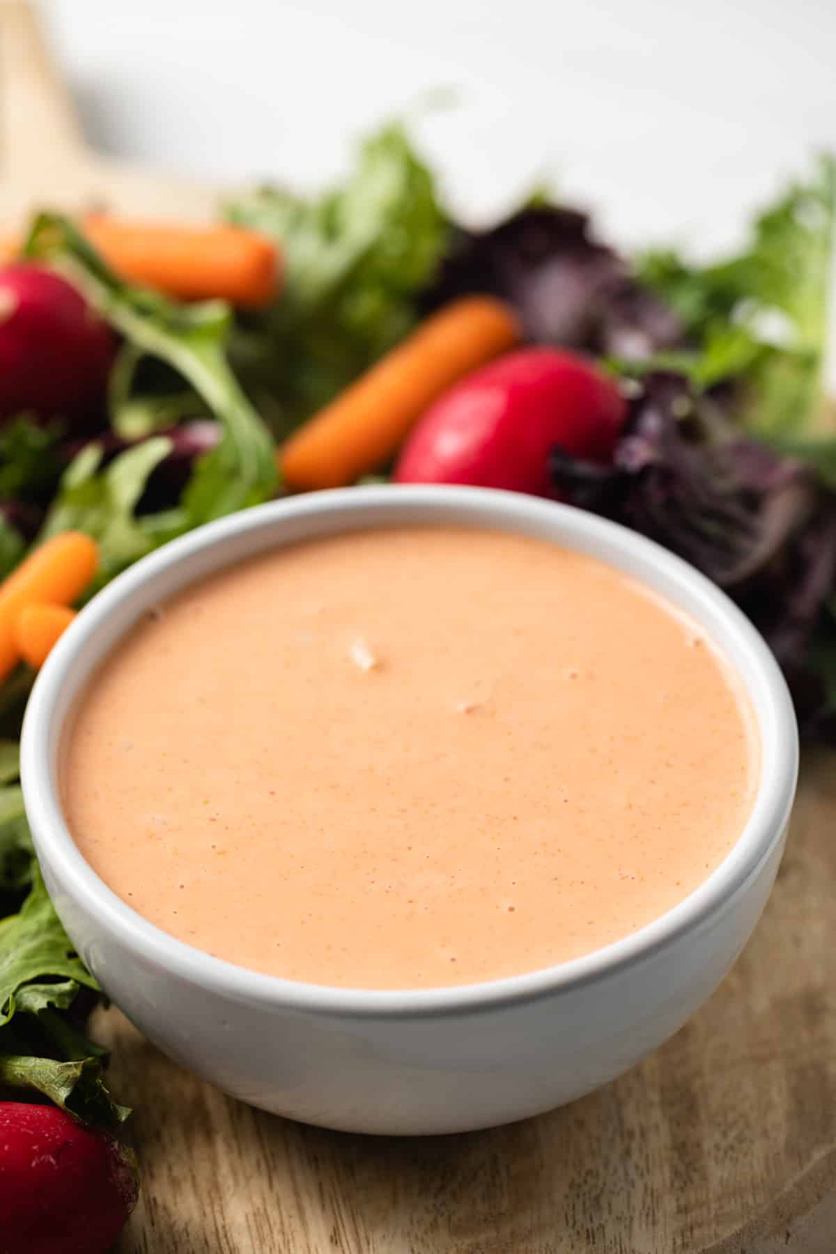 Side view of creamy russian dressing in white bowl.