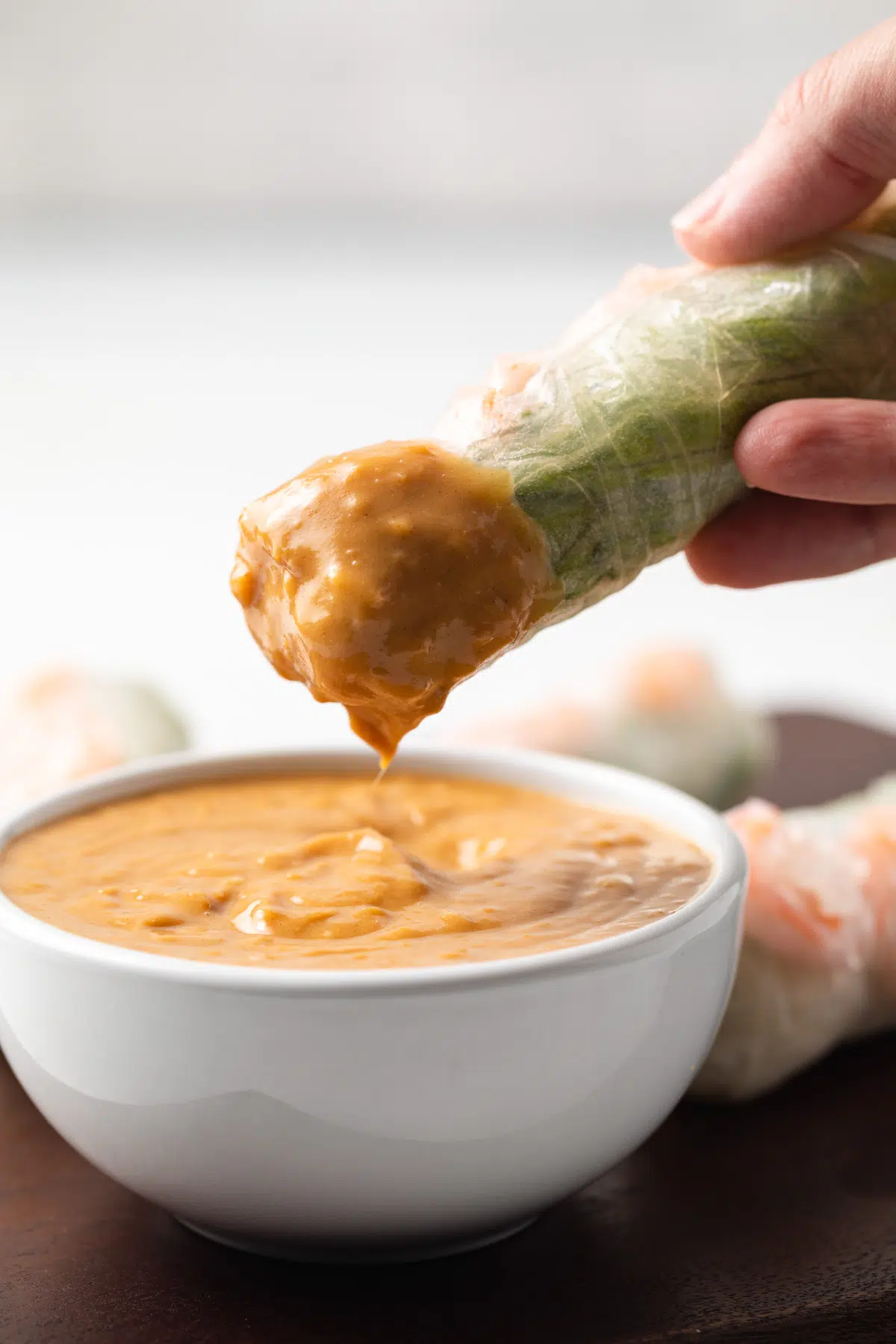 Spring roll dipped into peanut sauce.