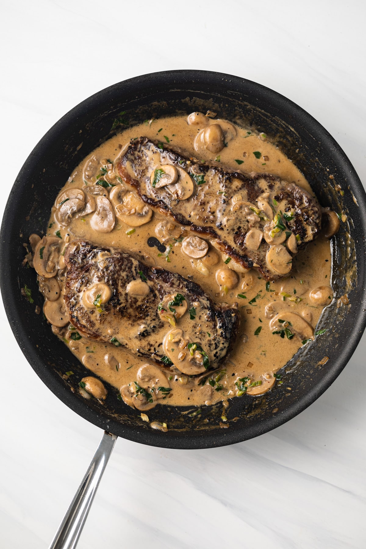 Steak with diane sauce in a skillet.