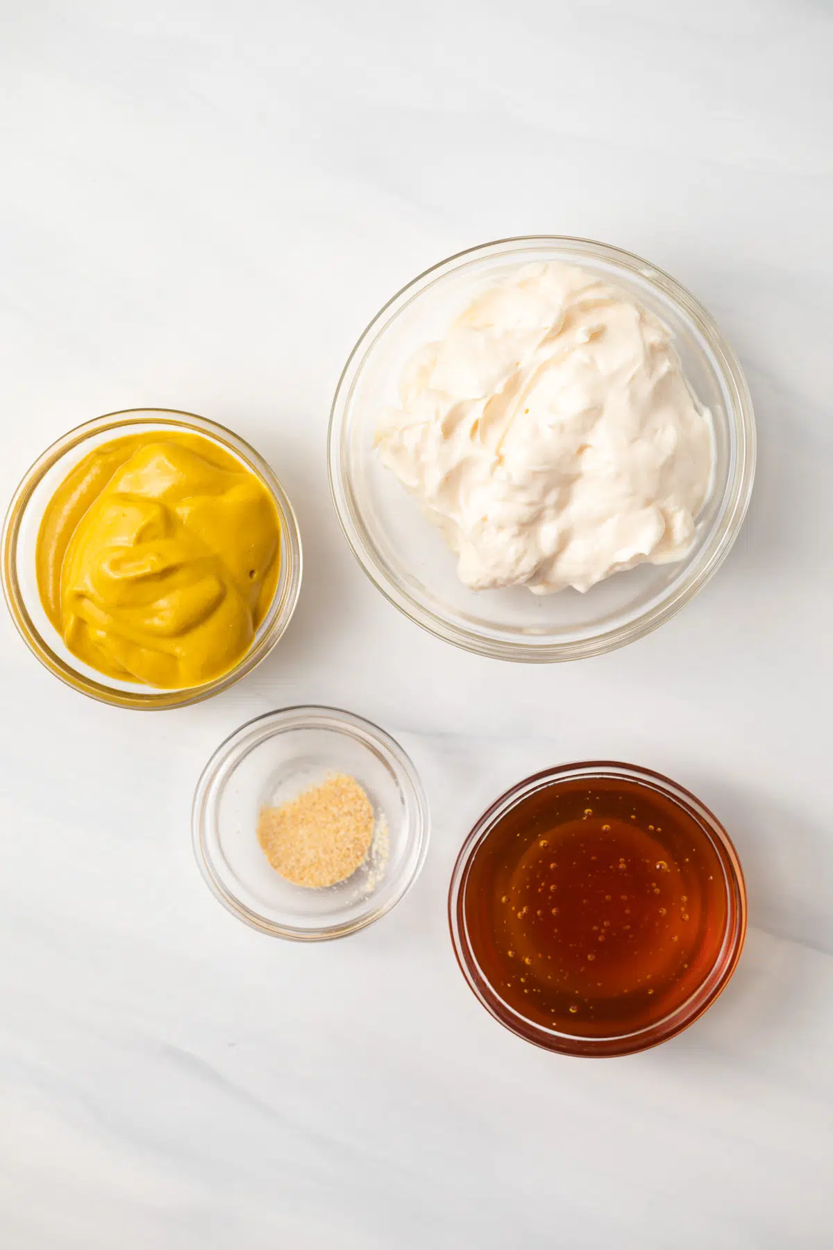 Ingredients for honey mustard in glass bowls.